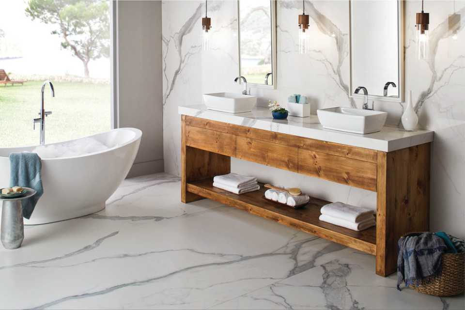 marble tile floor in bathroom with marble walls, wood vanity, and deep soak tubs